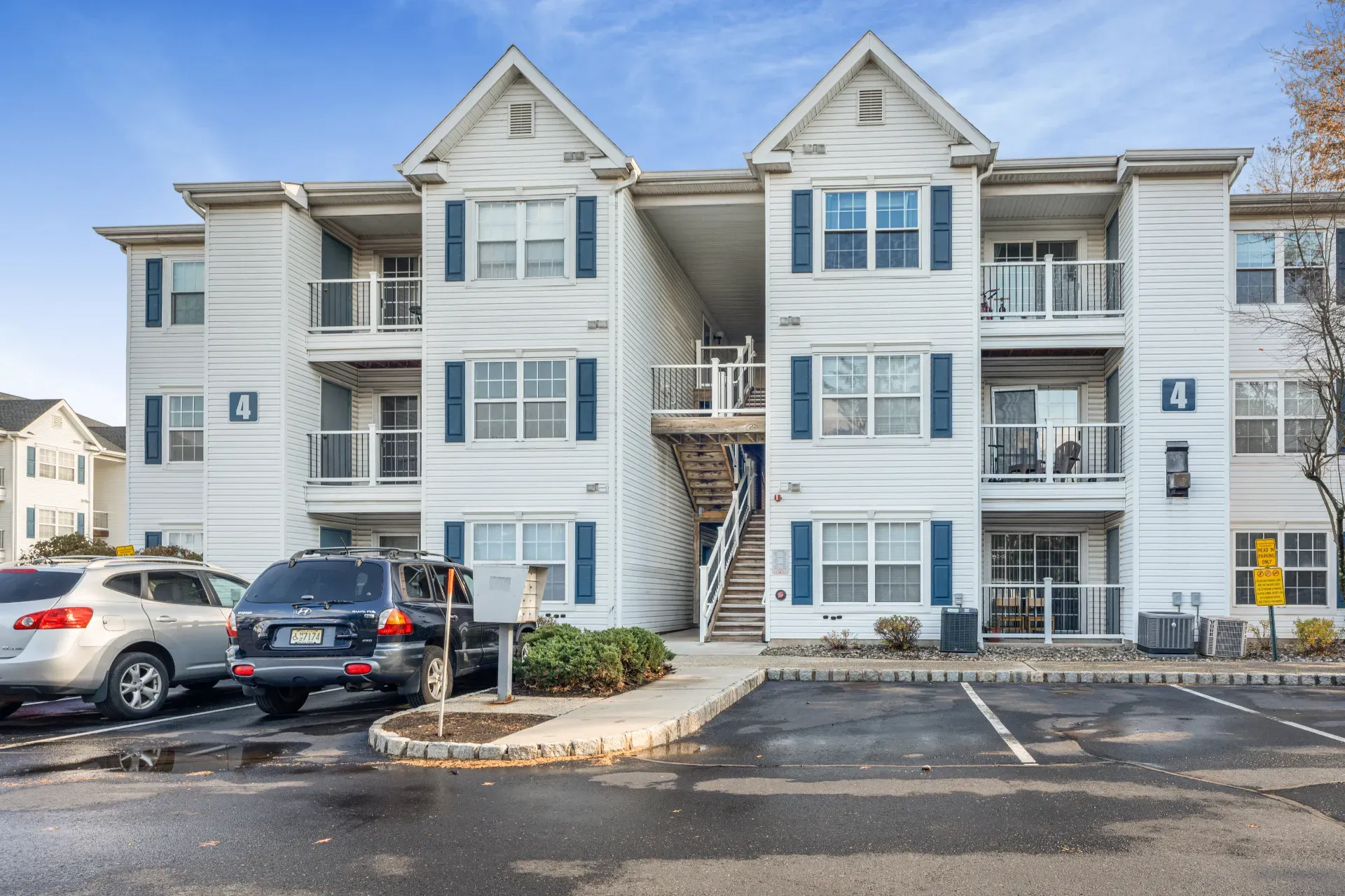 A three-story garden-apartment building in Edison, New Jersey, seen from its parking court
